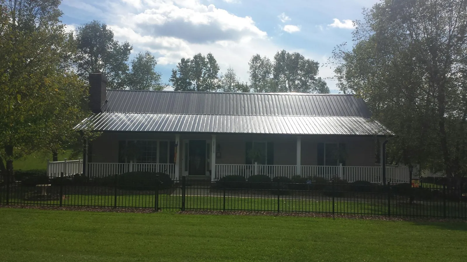 Gray metal roof on a brick ranch with a full width front porch — Gutter Guard Installation work by our crew in Sumter