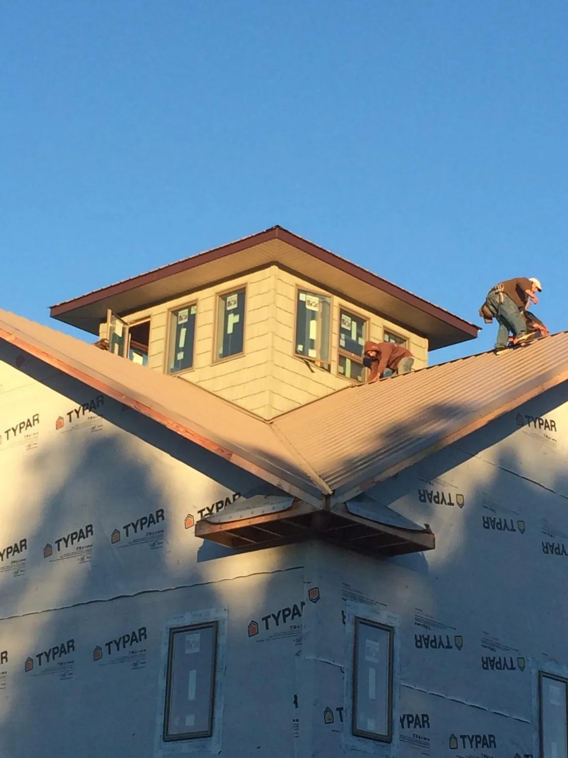 Roofers working around a rooftop cupola on a new metal roof at sunset — Roof Waterproofing in Sumter by Roofing Brothers
